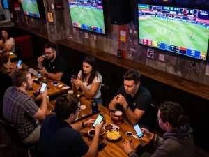 Engaged patrons comparing bets at a lively bar, showcasing https://www.dacsandatphanrang.com/ exciting sports betting atmosphere.